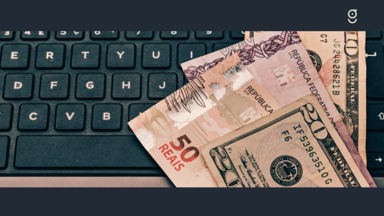 imagem ilustrativa de notas de reais e dólares sobre um teclado de computador
